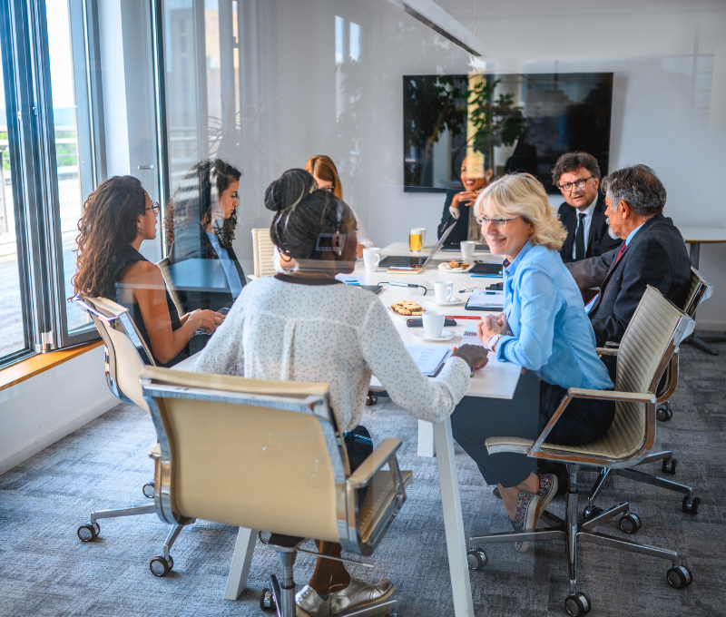 Group of people sat round a table in an office meeting room to show in-company training.